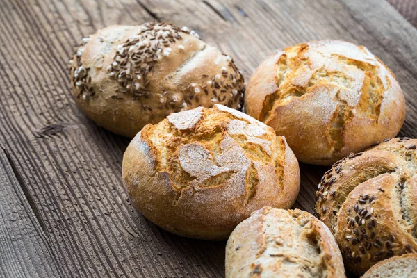 Olika sorters färskt bröd på träbord. — Stockfoto