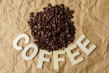 Kavrulmuş kahve çekirdekleri kahverengi ambalaj kağıt üzerinde. Kahve yazıt