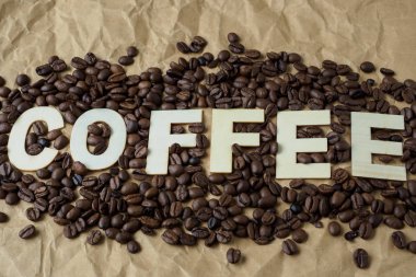 Kavrulmuş kahve çekirdekleri kahverengi ambalaj kağıt üzerinde. Kelime 