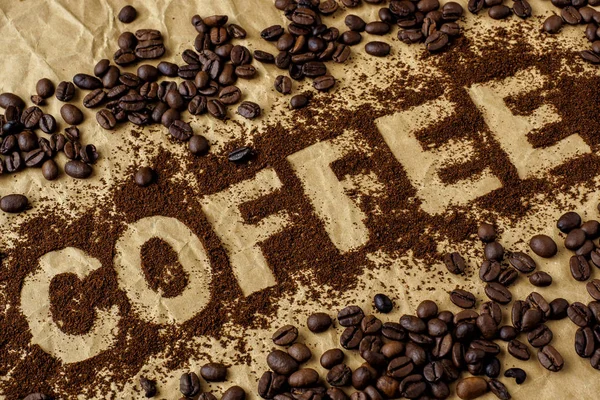 Geröstete Kaffeebohnen auf braunem Packpapier. das Wort "Kaffee" — Stockfoto