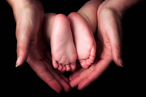 Pequenos pés de bebê nas mãos da mãe — Fotografia de Stock