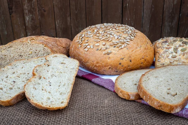 Färskt bröd på bordet. Bakat mörkt bröd och skivat bröd. — Stockfoto