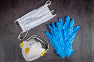 Koruyucu tıbbi maske, solunum cihazı ve siyah arka planda eldivenler. Kirliliğe karşı koruyucu ekipman, virüs, grip ve koronavirüs, covid 19.