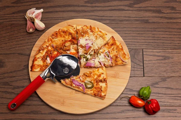 Tahta arka planda pizza kesicili pizza ve sarımsak ve biberle tahta kesme.