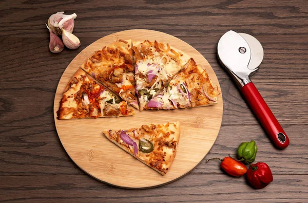 Tahta kesme tahtasındaki pizza üçgenleri ahşap arka planda, sarımsak ve acı biberli.