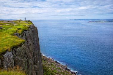 Kuzey İrlanda, İngiltere 'de uçurumun kenarında sırt çantalı bir turist duruyor.