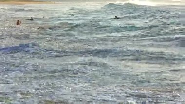 Hawaii, Oahu 'da kimliği belirsiz bir adamla kumsalda dalgalar çarpışıyor.