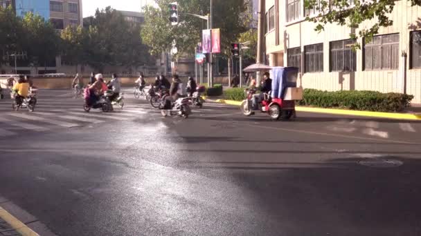 Группа мотоциклов, скутеров и велосипедов мчится через улицу по зеленому сигналу, типичное движение в китайском городе, Шанхае — стоковое видео