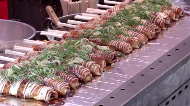 Okonomiyaki op houten stokken met sojasaus en mayonaise gegarneerd met groene ui op de Nishiki-markt, Kyoto — Stockvideo