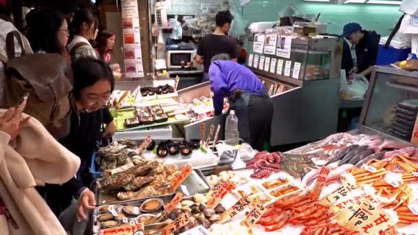 Kunden in einem Geschäft mit verschiedenen Meeresfrüchten auf dem Nishiki-Markt in Kyoto, Japan — Stockvideo