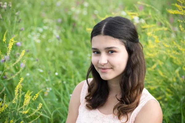 Flickan med mörkt hår på bakgrund av grönt gräs — Stockfoto