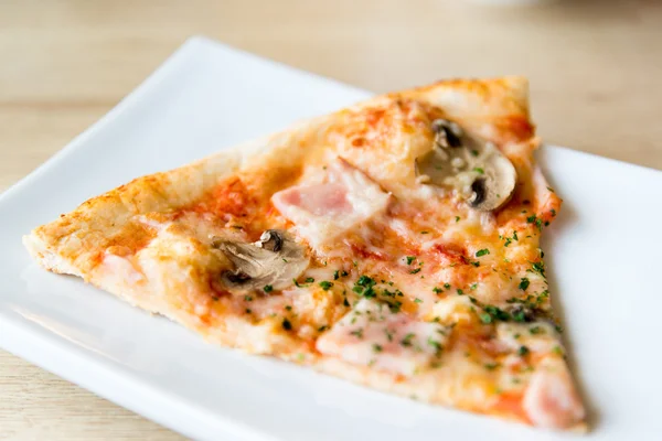 Piece of pizza with mushrooms and ham on plate — Stock Photo, Image