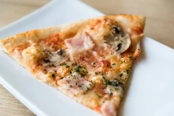 Piece of pizza with mushrooms and ham on plate — Stock Photo, Image