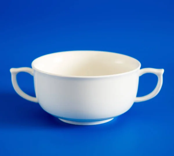 White cup of soup on blue background — Stock Photo, Image