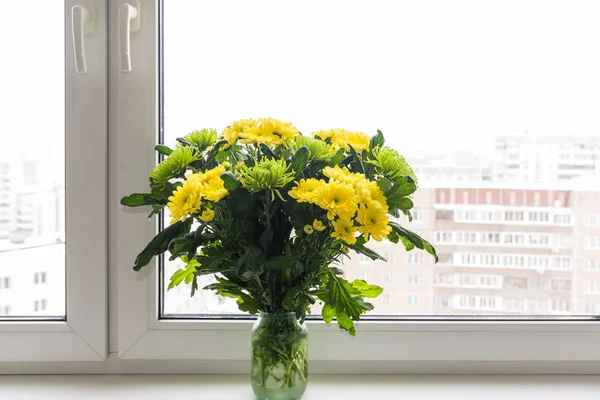 Csokor sárga krizantém és zöld áll ablakpárkányon — Stock Fotó