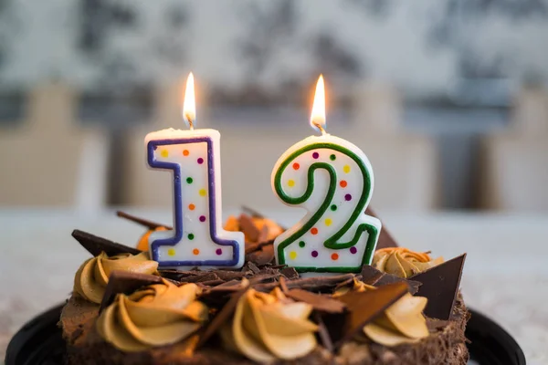 Chocolate cake with candles on day twelve of birth — Stock Photo, Image