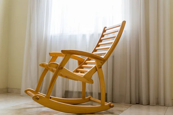 Wooden rocking chair возле окна в комнате — стоковое фото