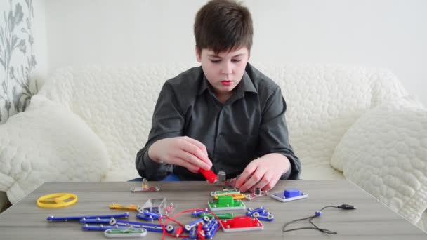 Teen pojke monterar den elektriska kretsen från konstruktör — Stockvideo