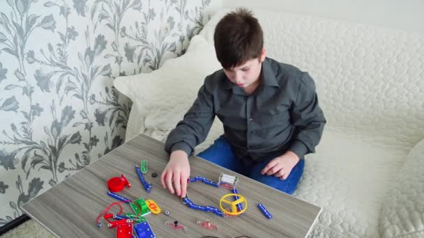 Pojke som studerar hanteringen av fläkt på elektriska krets i konstruktorn — Stockvideo