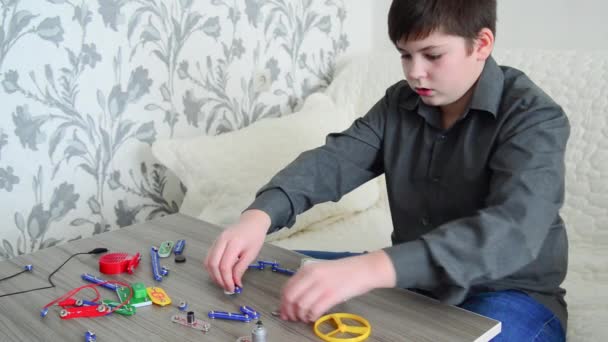 Boy assembles the electrical circuit from constructor — Stock Video