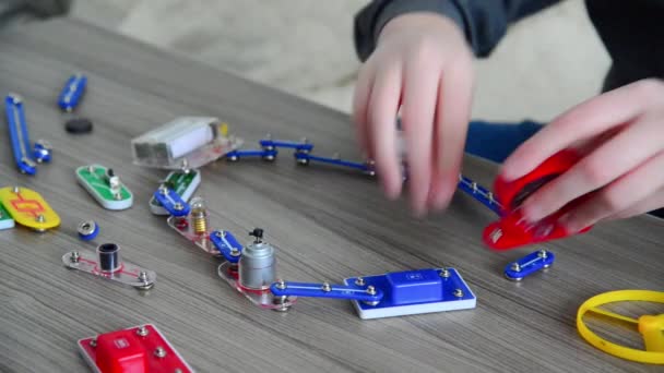 Мальчик собирает электрическую цепь от конструктора — стоковое видео