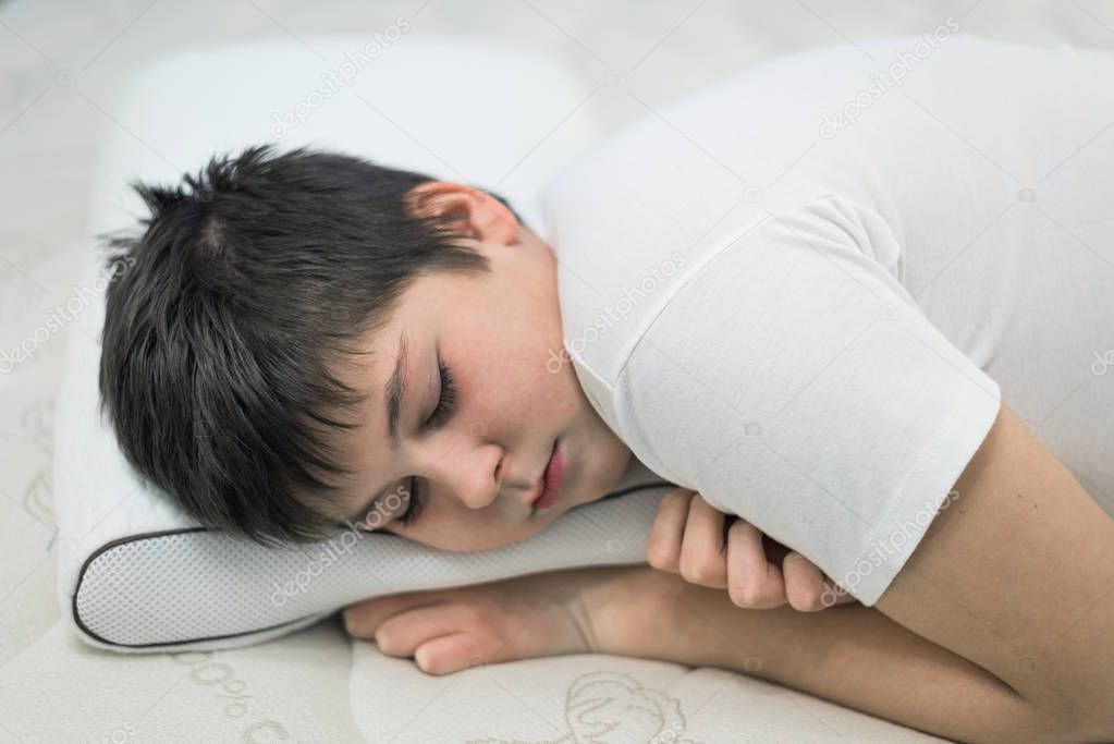 Boy teenager sleeping face down on anatomic pillow