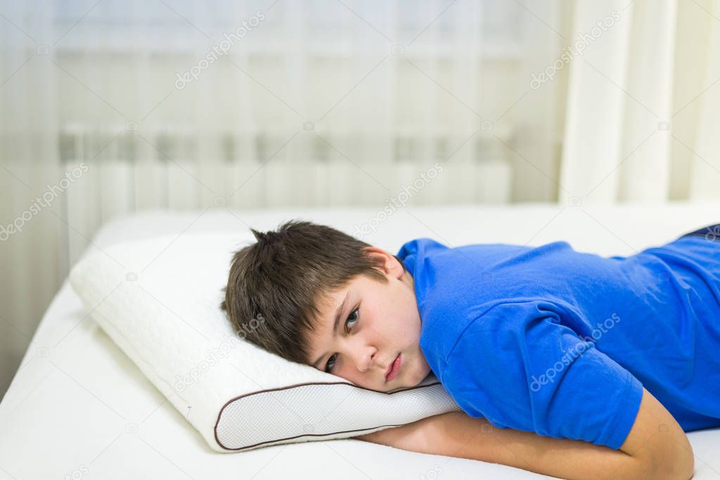 Boy teenager lying face down on anatomic pillow