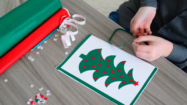 Teenager bastelt Weihnachtskarte aus farbigen selbstklebenden Papieren — Stockvideo