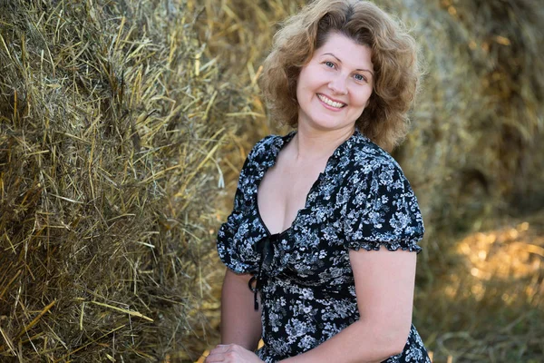 Усміхнена жінка в полі на тлі тюків соломи — стокове фото