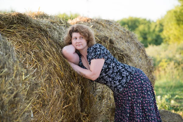 Beautiful pensive woman in field with straw bales — Stock Photo, Image