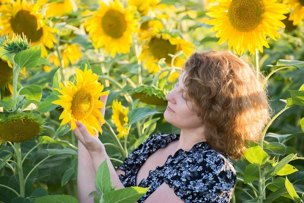 Erwachsene Frau mit lockigem Haar im Sonnenblumenfeld — Stockfoto