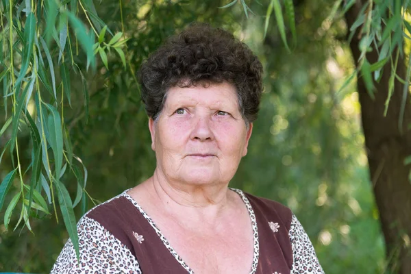 Mature woman with curly hair near weeping willow — Stock Photo, Image