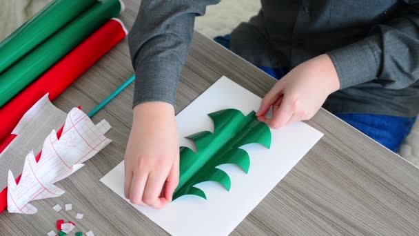 Tiener jongen kerstkaart van kleur papier maken — Stockvideo