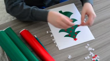 Çocuk bir kart Noel için yapar.