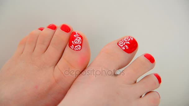 Женские ноги с красным лаком для ногтей и цветочным узором — стоковое видео