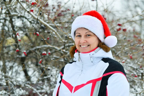 Gladlynt kvinna i cap jultomten på bakgrund av Viburnum — Stockfoto