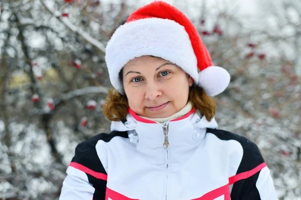 Žena v čepici Santa Claus poblíž stromu — Stock fotografie