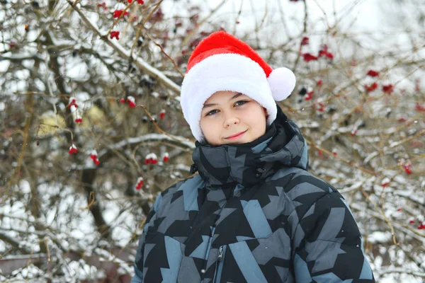 Adolescente menino em cap Papai Noel ao ar livre — Fotografia de Stock