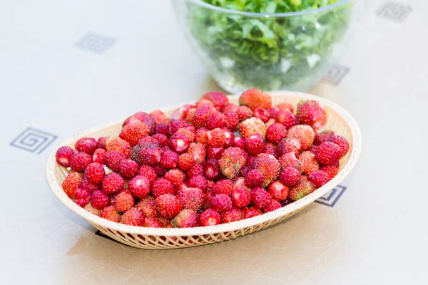 Rijpe wilde aardbei in rieten dienblad op een tafel — Stockfoto