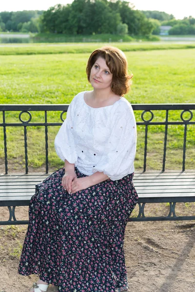 Donna seduta sulla panchina nel parco estivo — Foto Stock