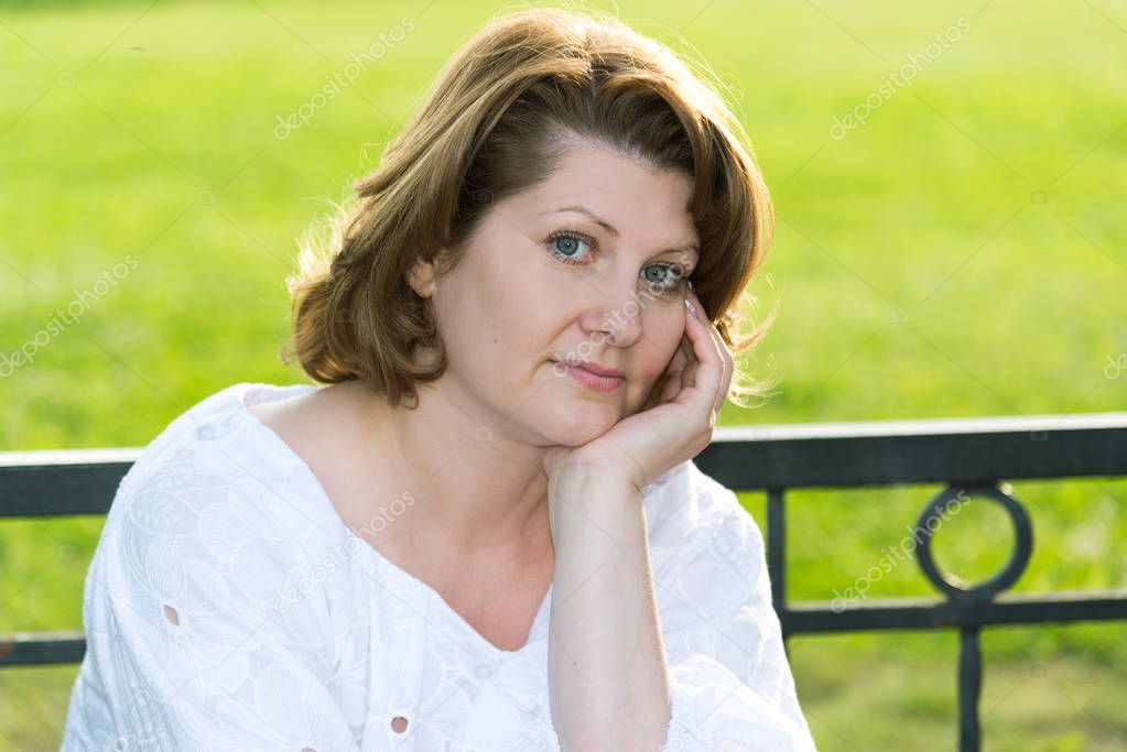 Cheerless woman in park on a bench