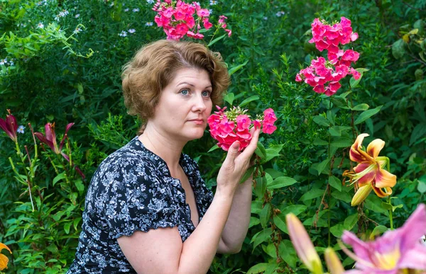 Γυναίκα εισπνέει άρωμα phlox στον κήπο — Φωτογραφία Αρχείου