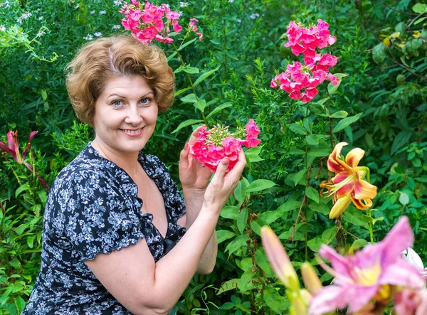 Mujer en el jardín rodeada de flores — Foto de Stock