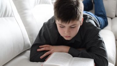 Genç odasında kanepede yatan bir kitap okuma.