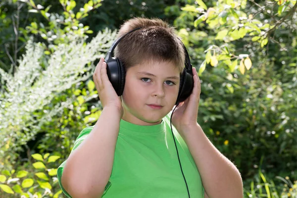 Boy poslouchal hudbu se sluchátky v parku — Stock fotografie