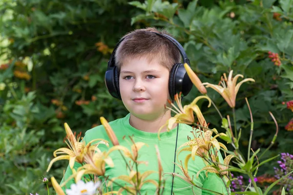 Portrét chlapce se sluchátky kolem daylily — Stock fotografie