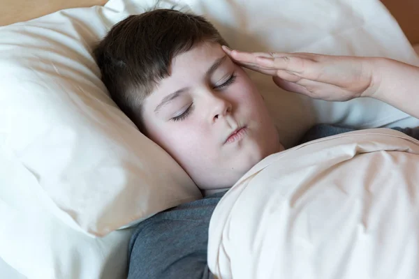 Хлопчик з головним болем лежить у ліжку — стокове фото