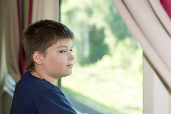 El chico mira por la ventana del tren. — Foto de Stock