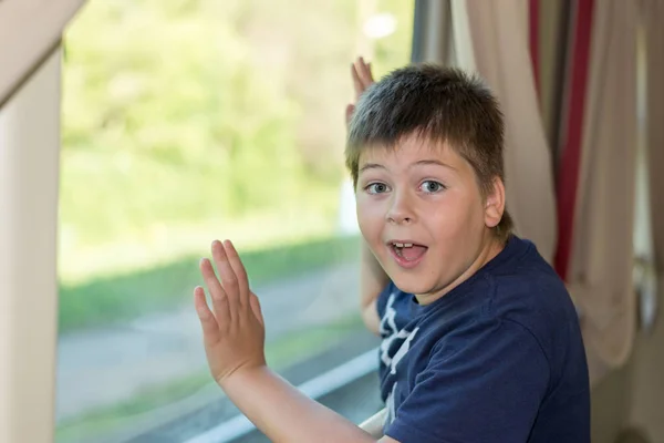 Chłopiec grymasy stojąc przy oknie pociągu — Zdjęcie stockowe