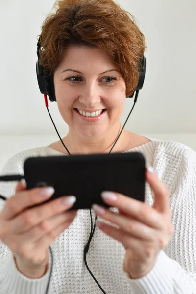 Mulher em fones de ouvido segurando smartphone — Fotografia de Stock